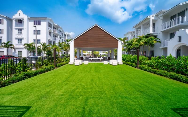 Landscaped event lawn leading to a covered pavilion with lounge seating at Sereno luxury apartments in Sunrise, FL