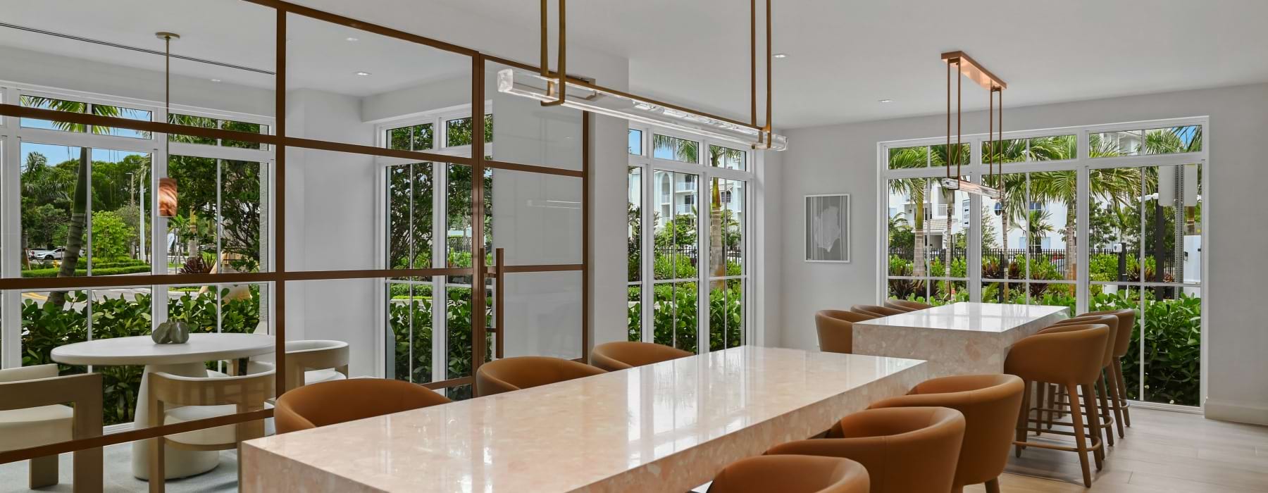 Resident coworking lounge with long terrazzo communal tables and floor-to-ceiling windows at Sereno apartments