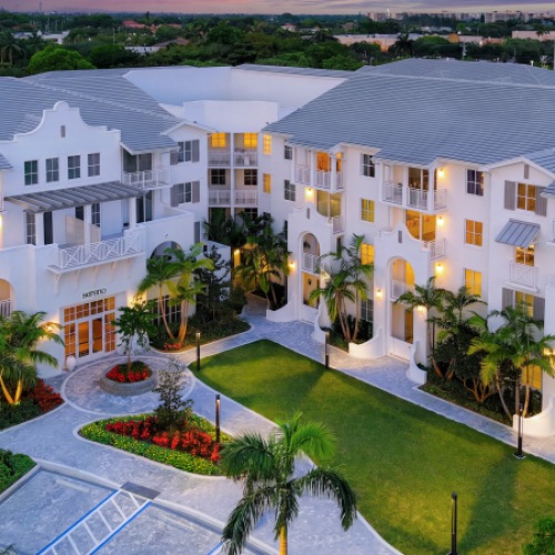 Aerial view of Sereno luxury apartments in Sunrise, FL at dusk with a paver courtyard and palm-lined entrance